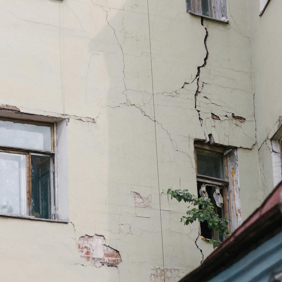 Fassade eines Altbaus mit sichtbaren Rissen und abgeplatztem Putz – typische Anzeichen für Bauschäden